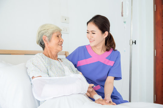 Senior asian female patient smiling with nurse who come to visit her at bed