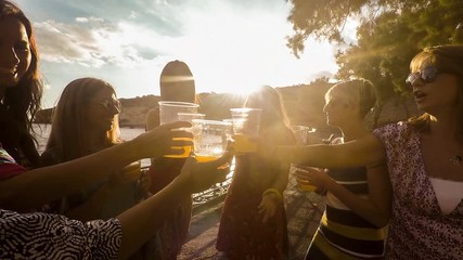 group of seven beautiful young women have a successful cocktail drink at the beach during a golden sunset outdoor all together to celebrate friendship and lifestyle in vacation. beauty happiness girls