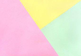 Three different color paper sheets ( pink, green, yellow ) with paper geometric pattern background. Top view, flat lay.
