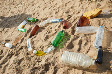 Old plastic bottles and other litter used to make word sos on sand of river bank