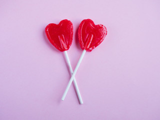 Two red heart lollipop on pink background