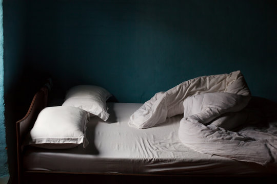 Bed with white blanket, blue walls in village house