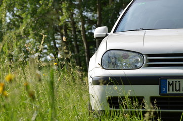 Front view of a white car outdoors between grass