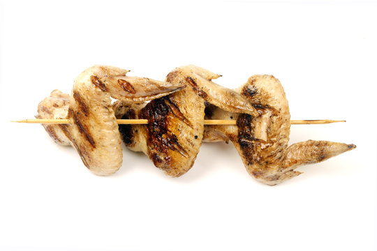 chicken wings fried on a grill strung on a skewer