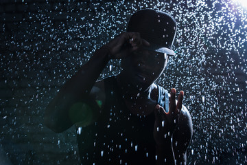 Rapper black man hooligan under rain - obrazy, fototapety, plakaty