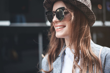 Fototapeta premium Profile portrait of smiling attractive woman. She is wearing stylish sunglasses and looking ahead with joy