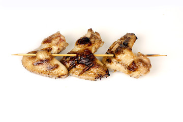 chicken wings fried on a grill strung on a skewer