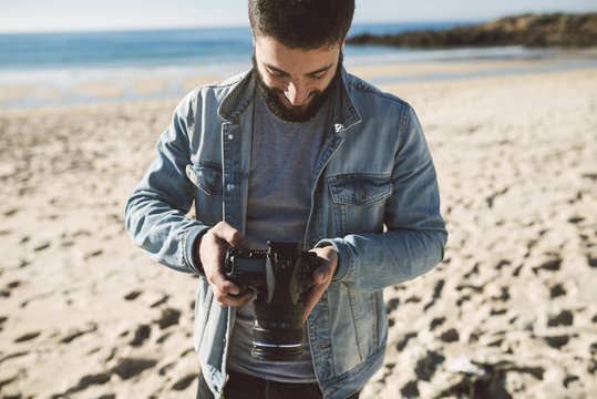 Casual young man looking a picture on his reflex camera