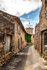 Fototapeta na wymiar narrow street, stone houses and clock tower of an ancient village