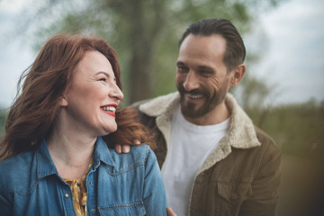Fototapeta premium Cheerful loving couple is dating outdoor. Husband is embracing wife with tenderness and smiling 