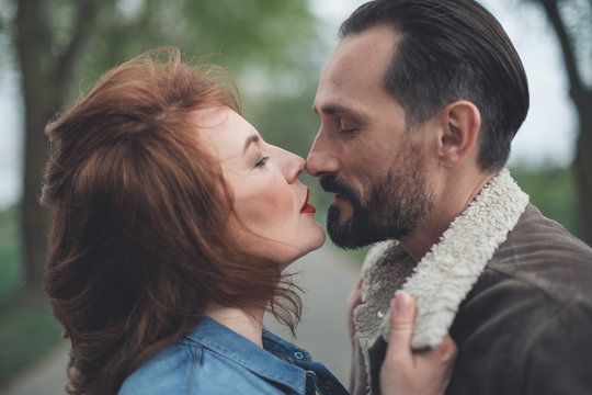 Profile of passionate man and woman kissing in the park. They are closing eyes with temptation 