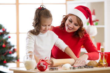 Adorable little child girl and mother baking Christmas cookies
