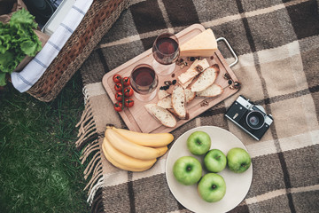 Enjoy your dinner in the nature. Close up top view of organic food and wineglasses on the blanket near picnic basket  