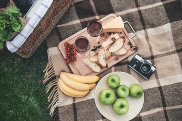 Foto auf Acrylglas Picknick Genießen Sie Ihr Abendessen in der Natur. Nahaufnahme von oben auf Bio-Lebensmittel und Weingläser auf der Decke in der Nähe des Picknickkorbs