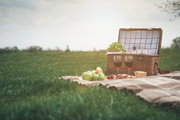 Enjoying nature and romance. Low angle of basket near healthy food and wineglasses on meadow. Copy...