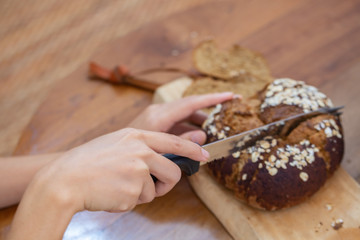 Chef is slicing brown delicious bread into pieces and ready to serve to customers in the bakery shop.
