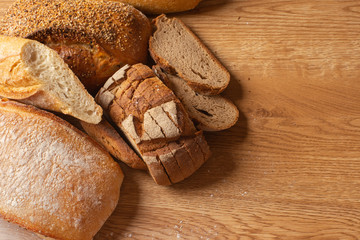 Various kind of delicious breads are arranged on brown wood background with copy space.