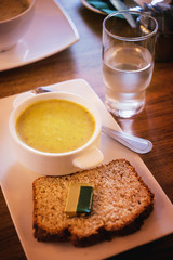 Mashed soup and bread with butter, glass of water on a dinner table