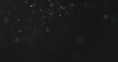 dust particles floating over black background with motion blur