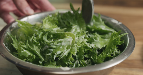 closeup mixing frillis salad leaves with caesar sauce