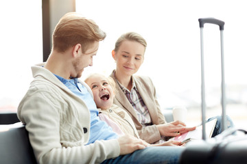Obraz premium Ecstatic little girl looking at her father duting talk with mother sitting near by while waiting for departure