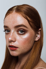 Portrait of a beautiful girl with long hair, makeup and freckles