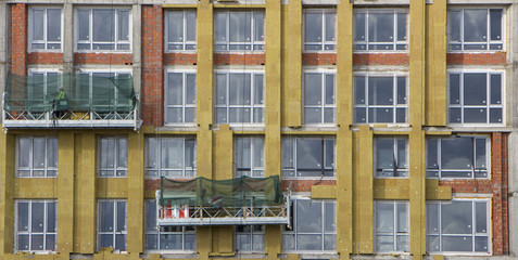 Fototapeta na wymiar Facade builders warm the walls of a modern high-rise building