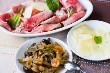 Roastbeaf, mushroom, cheese and salad on table.