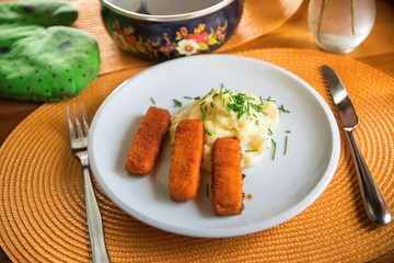 One portion of fried fish fingers and mashed potato.