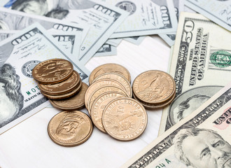 Dollar bills and coins on white wooden background.