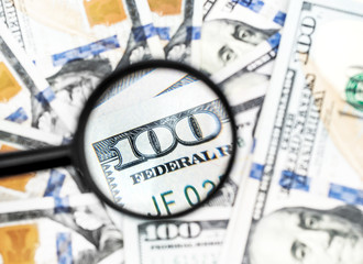 One hundred dollar bills under magnifying glass. Business concept.