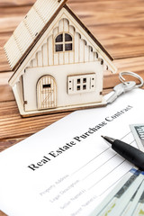 Contract for purchase house with model of house and money on the table. Top view.