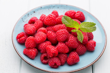 Fresh raspberries in a plate on a  vintage background.