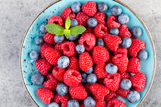 Fresh raspberries in a plate on a  vintage background.