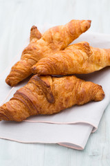 Tasty buttery croissants on old wooden table.