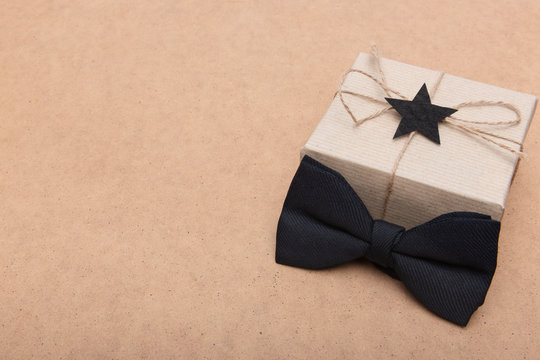 Happy Father's Day Background. Beautiful retro style gift box and black bow tie on brown background. Fathers day still life. - Powered by Adobe