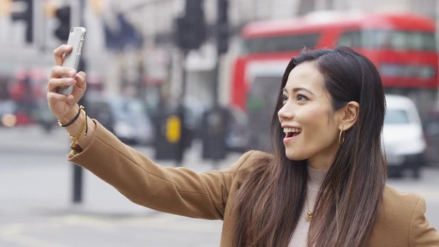 Young asian female in the city taking a selfie on her phone