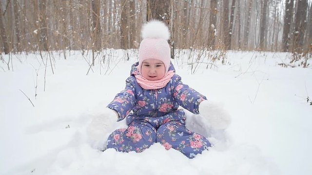 Little girl is playing with snow in the park