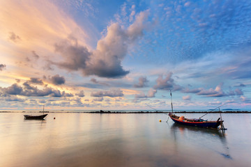 Fishing boat in perfectly calm sea water like glass with the clouds in the sky, long Exposure taken during sunrise