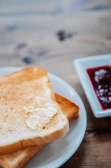 Slice of toasted bread with butter and fruit jam, close up shot