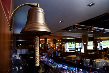 A bell with a woven rope on the background of the bar.