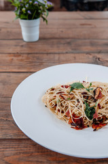 Spaghetti pasta bacon with dried spicy chilli on white plate on the wood table from side view