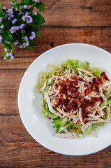 Grilled chicken Salad with green lettuce in white plate on wood table top view shot