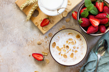 Healthy breakfast - whole grain flakes, milk and fresh strawberries on stone or slate background. The concept of nutrition health. Copy space, top view flat lay background.