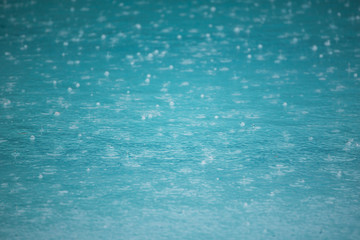 raining on swiming pool, rain drops on pool.