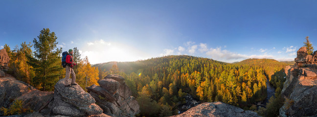 Backpacker on top of a rock fall at dawn. Cylindrical panorama 360 degrees