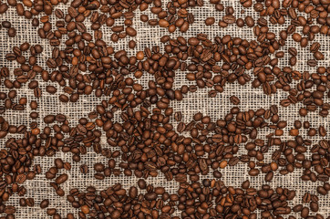 Coffee beans on burlap cloth background, top view photo.
