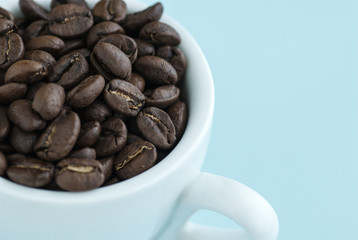 Fried brown coffee beans in a white cup.