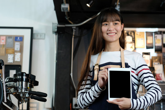 Young asian woman barista holding tablet at cafe counter background, food and drink concept, small business