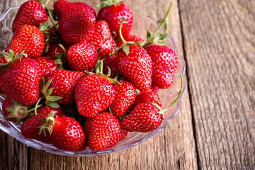Strawberry in glass bowl on rustic wooden table